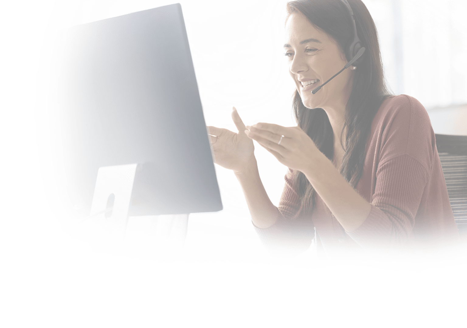 Positive Latin businesswoman in headphones talking on video call at monitor, speaking, laughing, moving hands. Cheerful online teacher giving business training, webinar