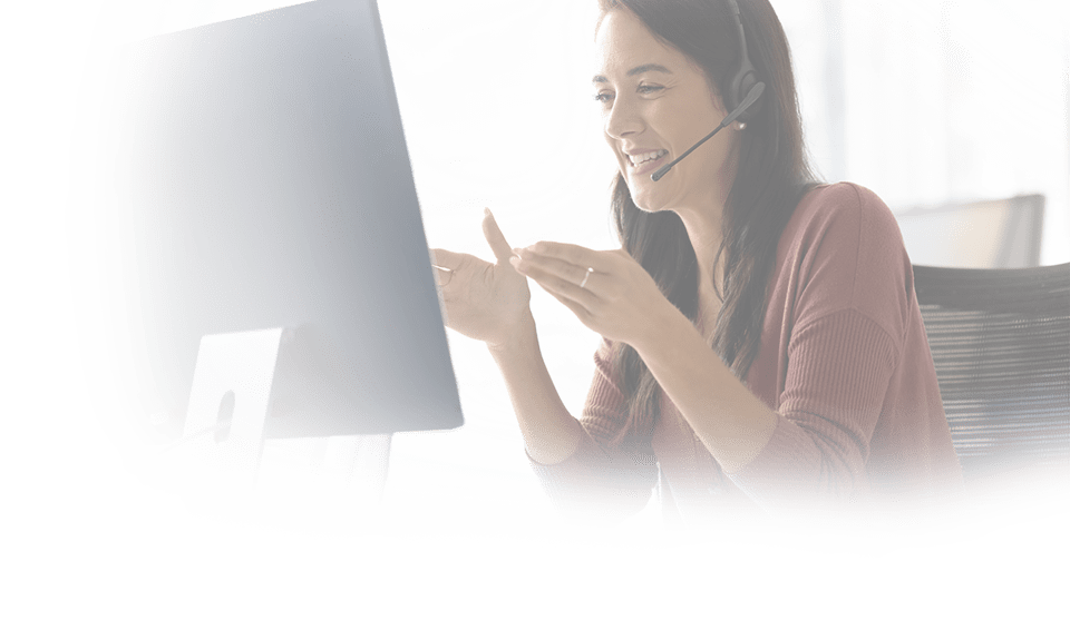Positive Latin businesswoman in headphones talking on video call at monitor, speaking, laughing, moving hands. Cheerful online teacher giving business training, webinar
